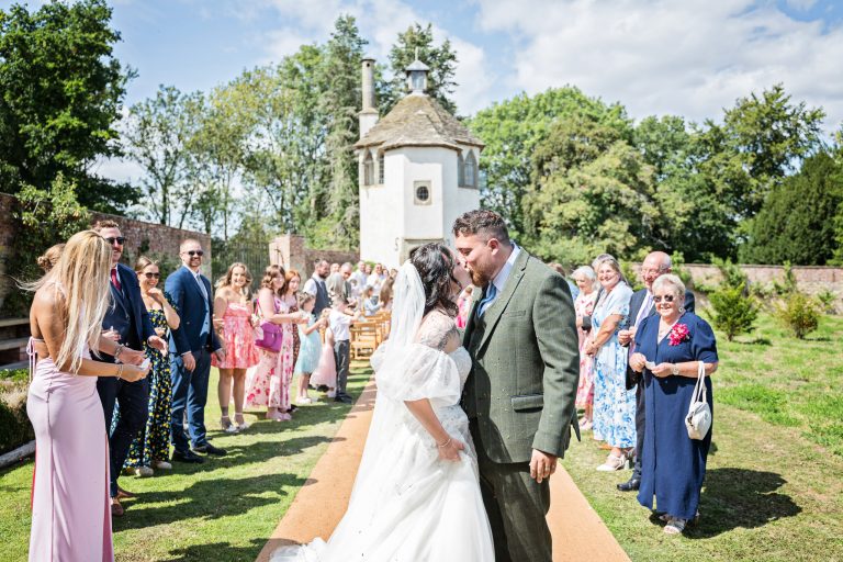 A bride & groom kiss after walking down the confetti isle