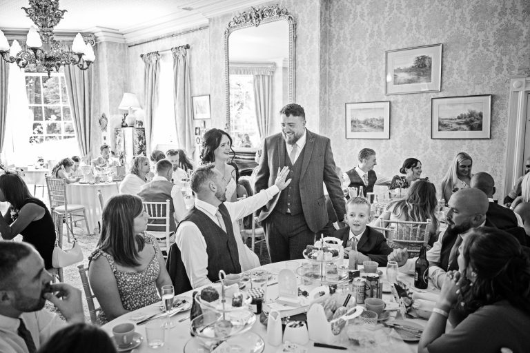 B&W image of a Bride and Groom in a Georgian dining room full of wedding guests