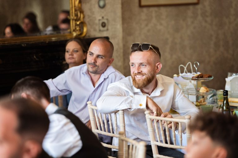 A Georgian dining room full of wedding guests listening to the speeches.