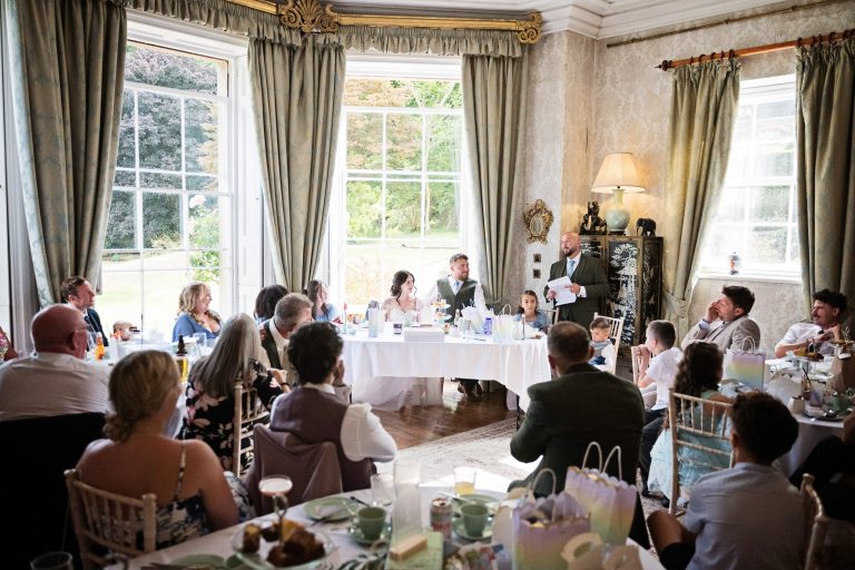 A Georgian dining room full of wedding guests listening to the speeches.
