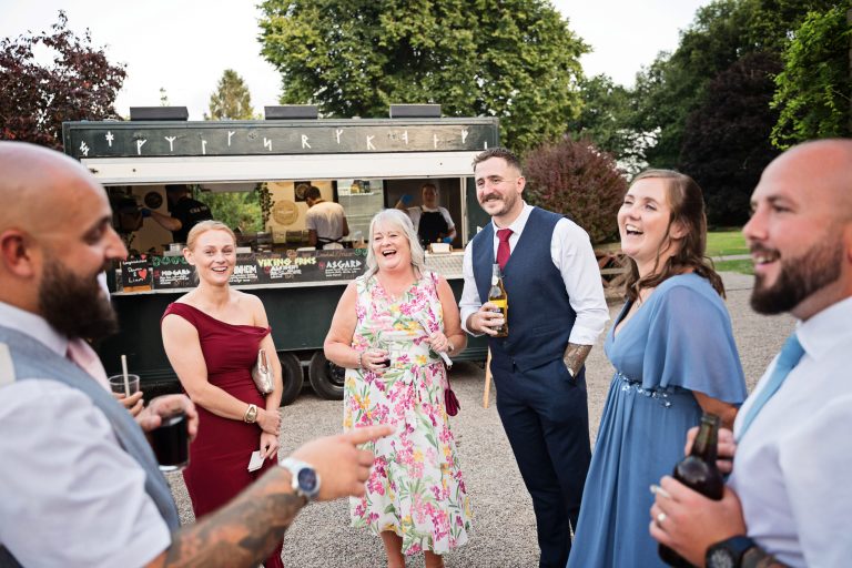 People laughing and smiling as a man tells a joke. A viking fries catering truck is behind them