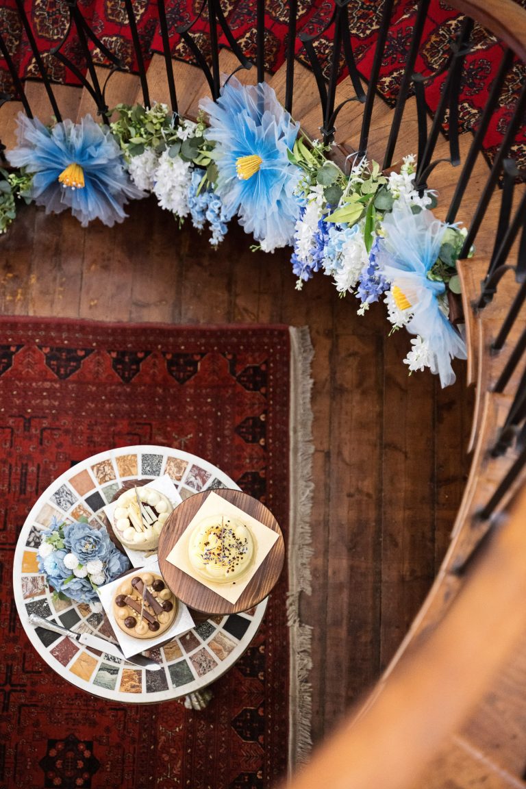 A view downwards from the top of a spiral staircase of the staircase and wedding cake. Flowers line the edge of the staircase